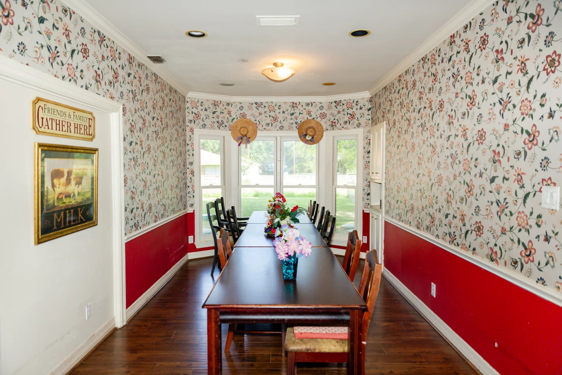 A dining room with red walls and floral wallpaper.